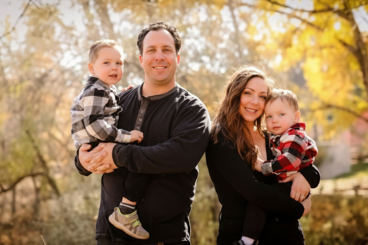 Family of four outdoors with autumn leaves in the background