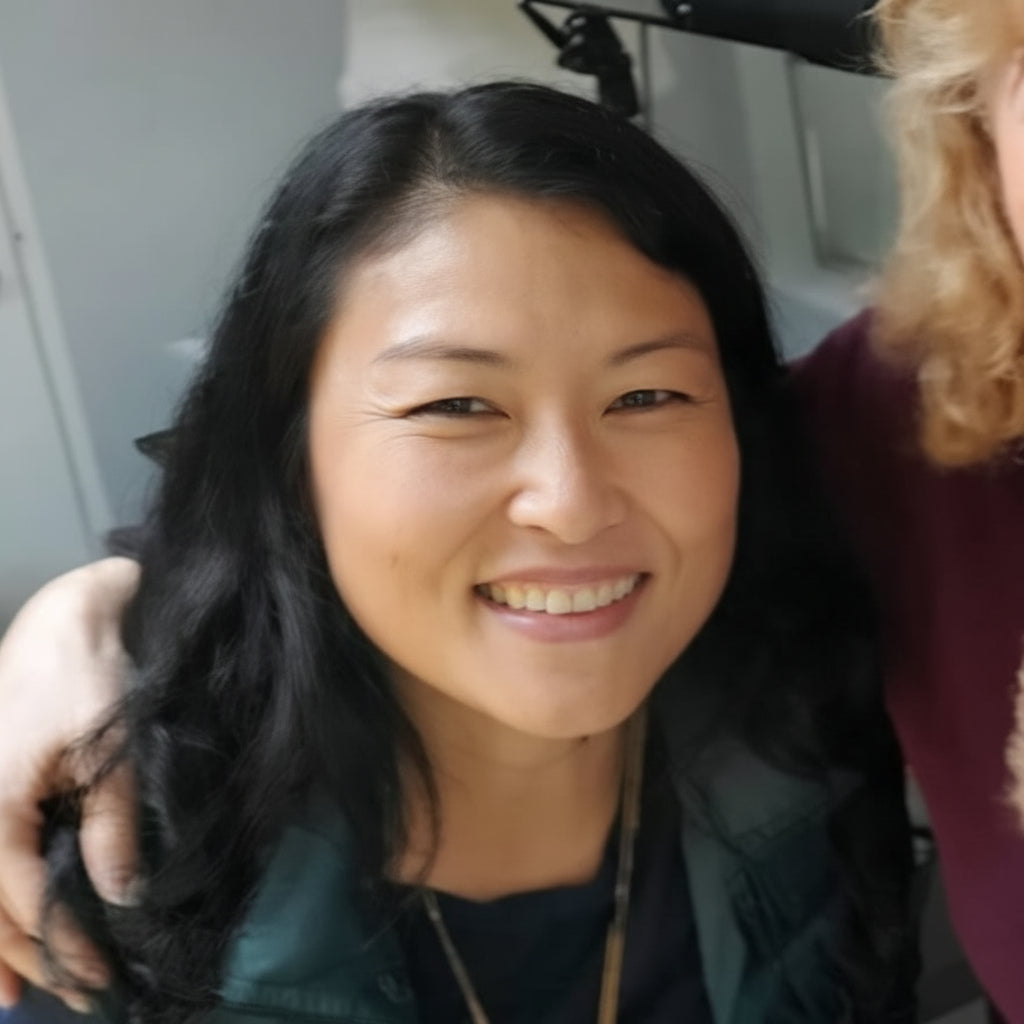 Woman with dark hair smiling, wearing a green jacket.